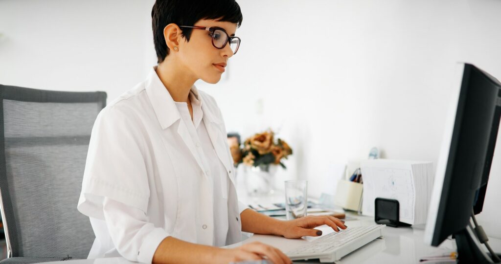 Beautiful female doctor typing receipt for patient