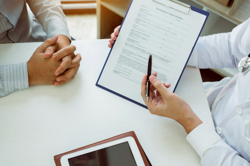 Confident female doctor reviews patient medical information and pointing to medical forms.