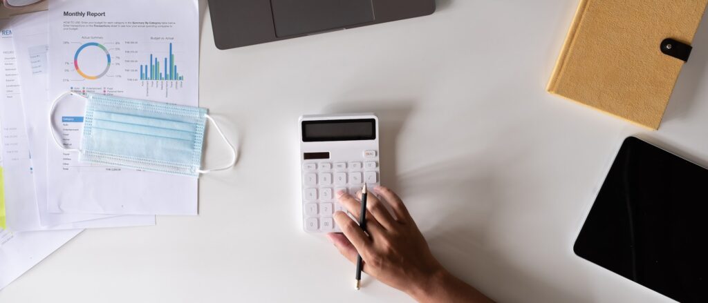 Top view hand of accountant using calculator on workplace, calculator and plant potted on white